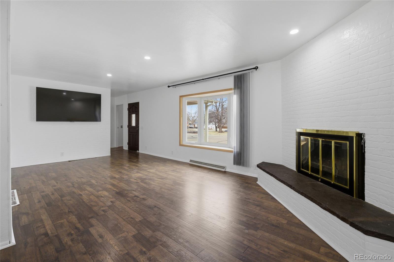 308 Fifth Street Dacono, CO 80514 - Photo 7 of 29 a view of a livingroom with wooden floor and a flat screen tv