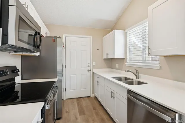 a kitchen that has a sink a stove and cabinets