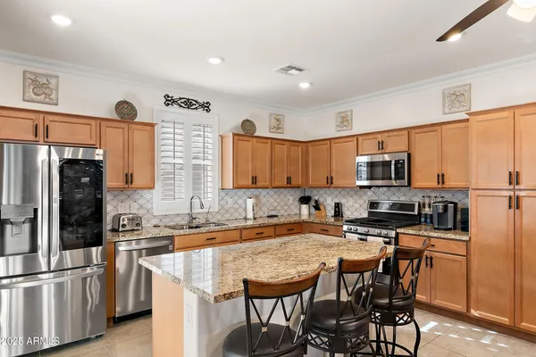 a kitchen with stainless steel appliances granite countertop a sink a stove a refrigerator cabinets and chairs