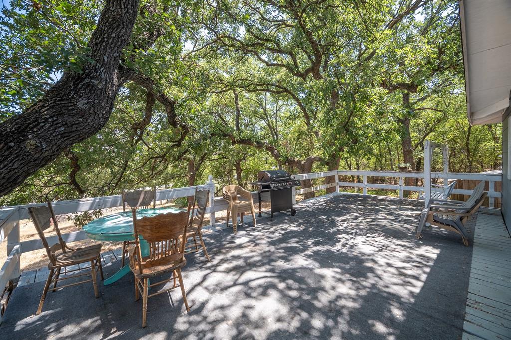 1285 Clark Road Gainesville, TX 76240 - Photo 14 of 20 Expansive outdoor deck area with white railings, surrounded by mature trees, offering a serene setting