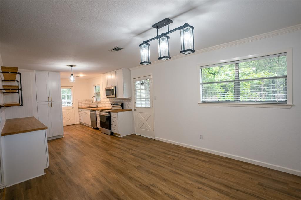 1285 Clark Road Gainesville, TX 76240 - Photo 2 of 20 The open-concept living space features hardwood floors, white walls, and a large window with natural light