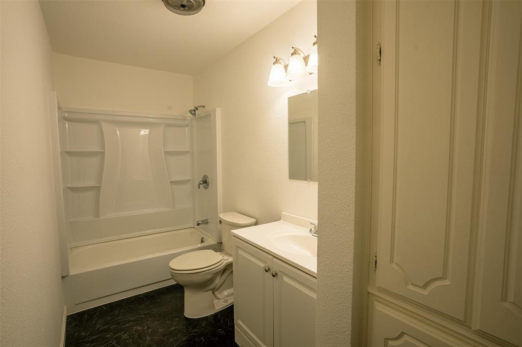 1285 Clark Road Gainesville, TX 76240 - Photo 4 of 20 Bathroom with white bathtub and shower unit, a toilet, a vanity with a sink, and a built-in storage cabinet