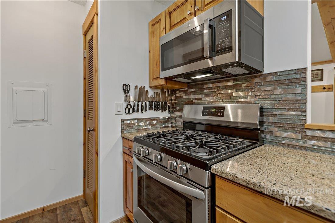 79 Sunset Loop Cascade, ID 83611 - Photo 12 of 44 Stainless steel range with a coordinating microwave, light wood-finish cabinetry, and granite countertops