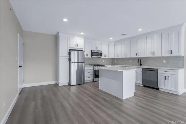 a kitchen with wooden floors white cabinets and stainless steel appliances