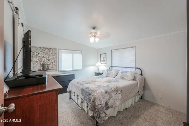 a bedroom with a large bed and a flat tv screen on dresser