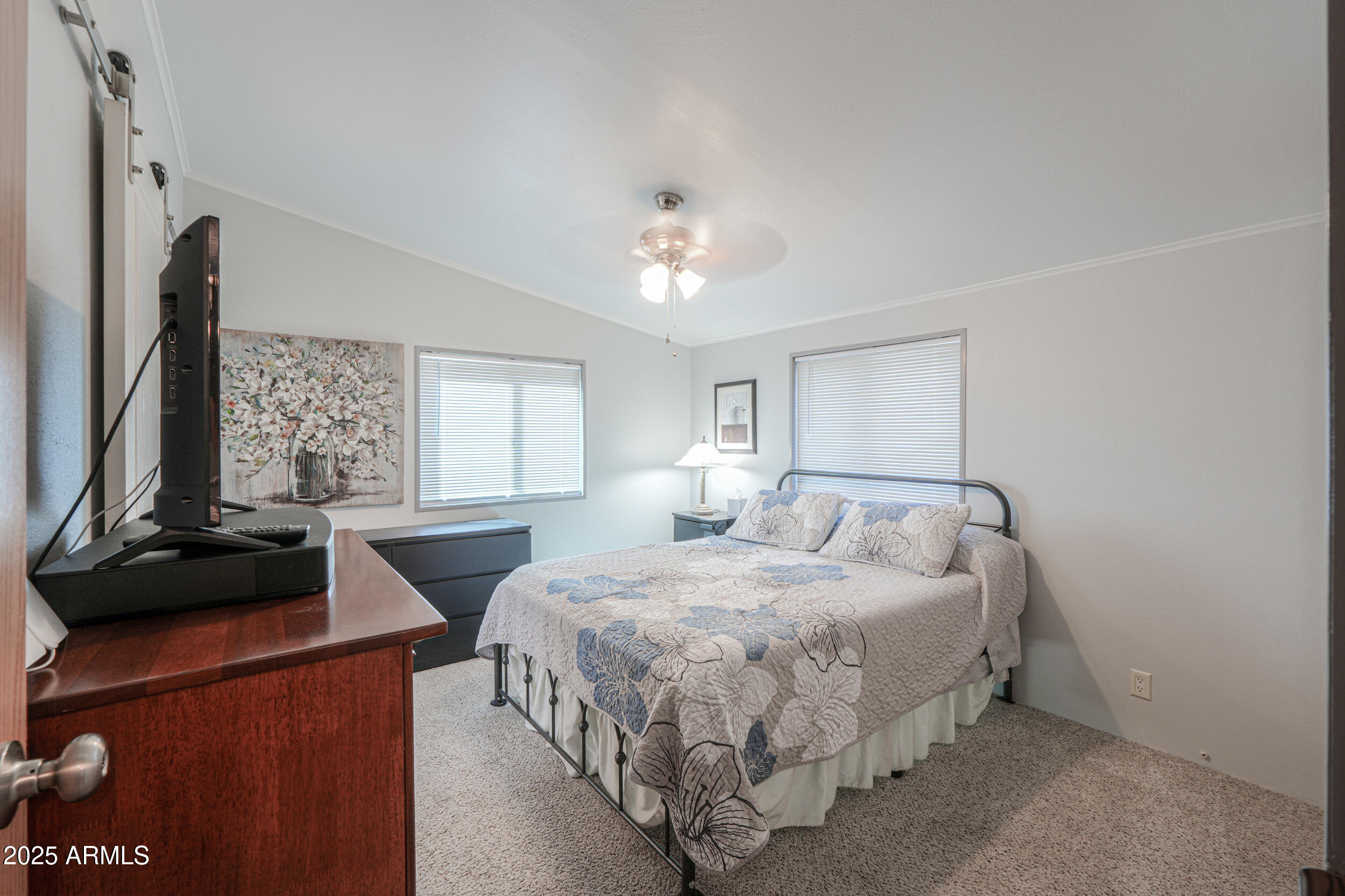 2208 West Baseline Avenue, Unit 40 Apache Junction, AZ 85120 - Photo 11 of 30 a bedroom with a bed and a flat tv screen on a dresser