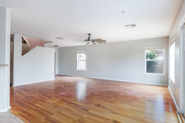 an empty room with wooden floor and windows