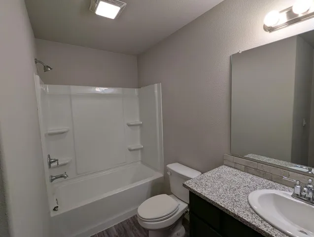 a bathroom with a granite countertop sink toilet a mirror and shower