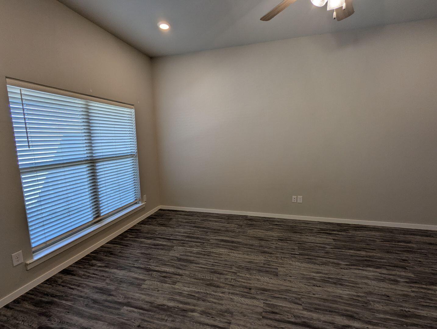 1628 133rd Street, Unit A Lubbock, TX 79423 - Photo 2 of 11 a view of an empty room with wooden floor and a window