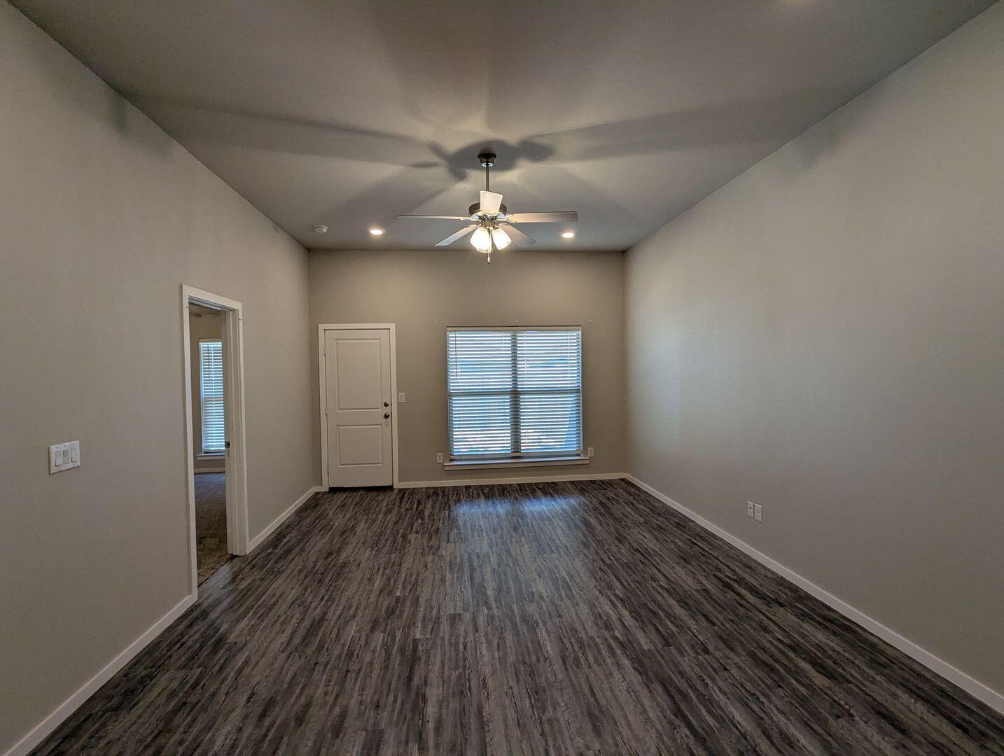 1628 133rd Street, Unit A Lubbock, TX 79423 - Photo 3 of 11 wooden floor in an empty room with a window