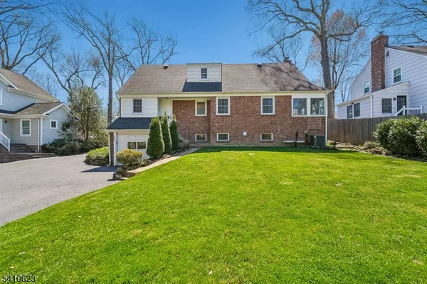 a view of a yard in front of a brick house with many windows