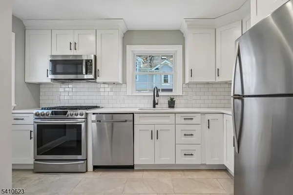 a kitchen with stainless steel appliances white cabinets white stove a sink and a refrigerator