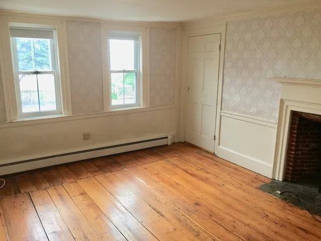 a view of empty room with wooden floor and fireplace