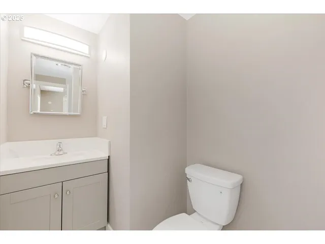 a bathroom with a toilet sink vanity and mirror