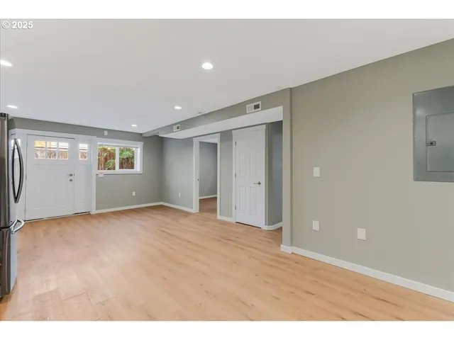 a view of an empty room with window and wooden floor