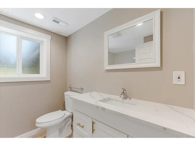 a bathroom with a toilet a sink a vanity and mirror