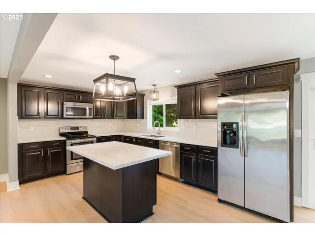a kitchen with stainless steel appliances granite countertop a stove a refrigerator and a sink