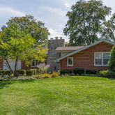 a backyard of a house with lawn chairs plants and tree