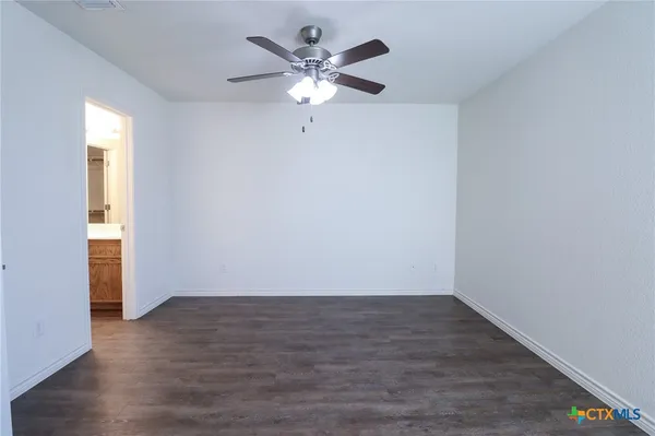 an empty room with wooden floor and a ceiling fan