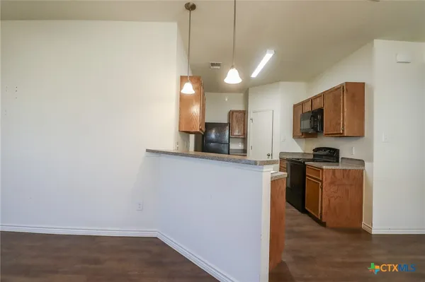 a kitchen with granite countertop a sink a refrigerator and cabinets