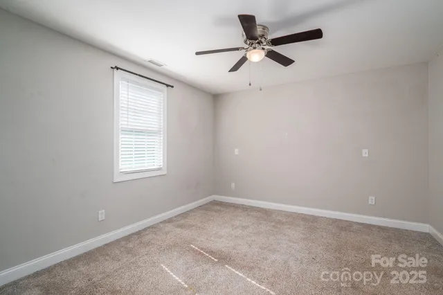 a view of a big room with a ceiling fan and windows