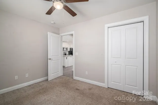 an empty room with closet and a chandelier fan