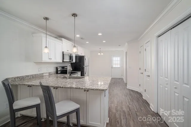 a kitchen with kitchen island granite countertop a sink cabinets and wooden floor