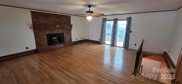 a view of a livingroom with wooden floor and a fireplace