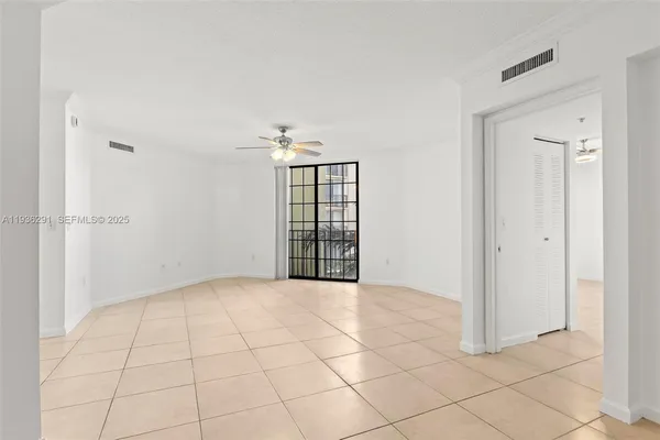 an empty room with chandelier fan and windows