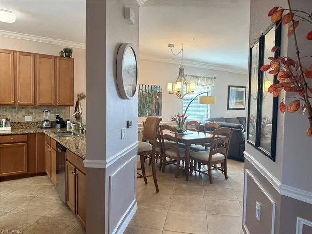 a kitchen with stainless steel appliances granite countertop a stove top oven a sink a dining table and chairs with wooden floor