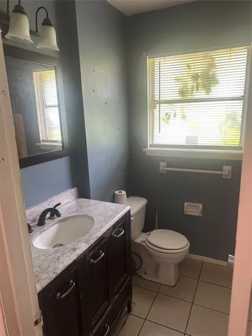 a bathroom with a granite countertop sink a toilet and a window