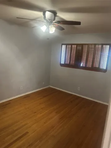 a view of an empty room with window and wooden floor