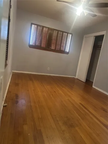 a view of an empty room with wooden floor and window