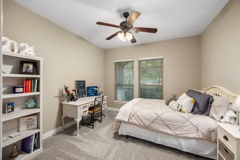 a bedroom with a bed bookshelf and a large window