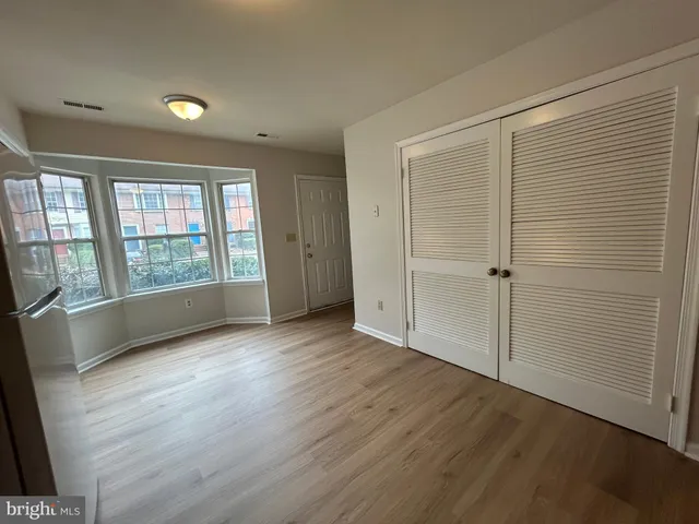an empty room with wooden floor and windows