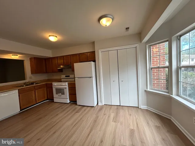 a kitchen with refrigerator and wooden floor
