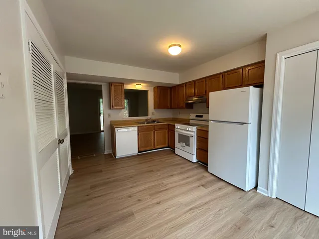 a kitchen with a refrigerator a stove top oven and wooden floor