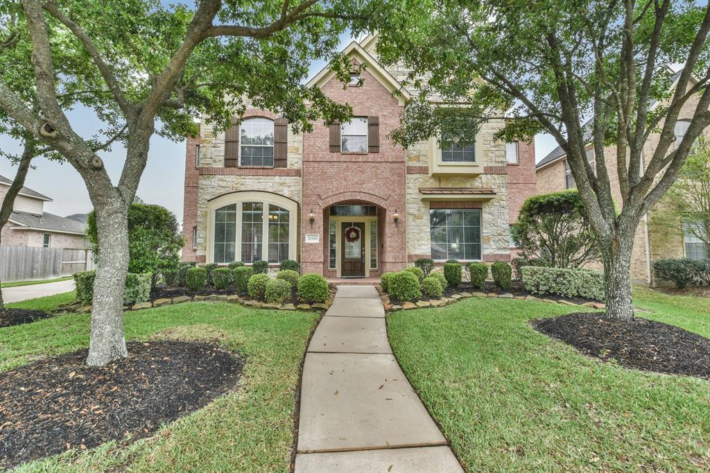 Beautiful curb appeal with brick, stone, shutters, professional landscaping and shade trees