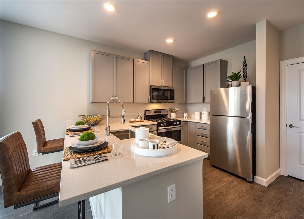 72 Flint Street, Unit 1106 Salem, MA 01970 - Photo 3 of 13 a kitchen with stainless steel appliances granite countertop a refrigerator a stove a sink a dining table and chairs