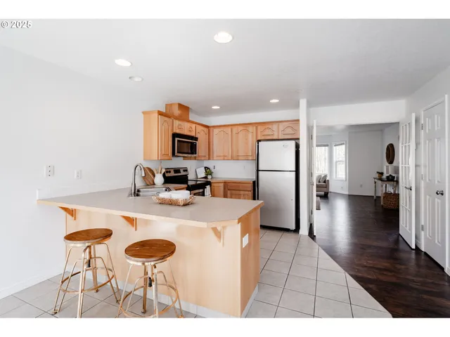 a kitchen with stainless steel appliances granite countertop a refrigerator a stove a sink dishwasher and a dining table with wooden floor