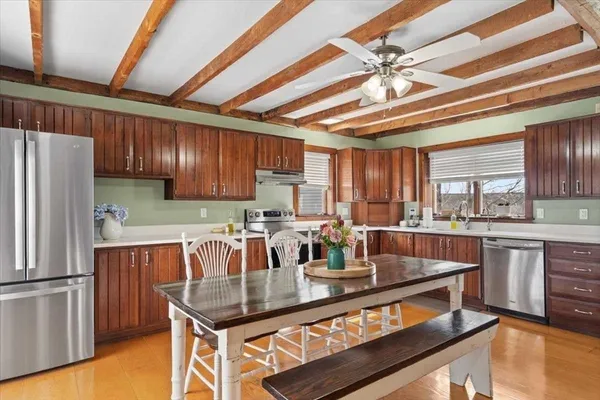 a room with stainless steel appliances kitchen island granite countertop a table chairs and a refrigerator