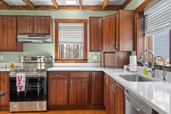 a kitchen with stainless steel appliances granite countertop a sink a stove and a wooden cabinets