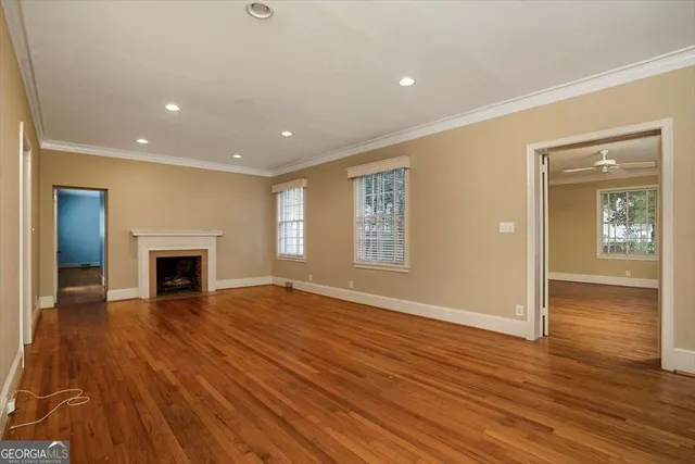 an empty room with wooden floor fireplace and windows
