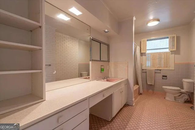 a spacious bathroom with a sink a toilet a shower and a mirror