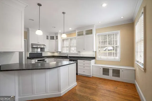 a kitchen with stainless steel appliances granite countertop a sink a stove and a wooden floors