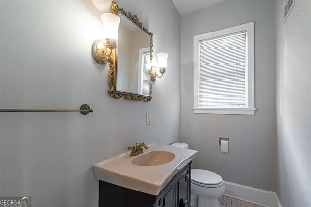 a bathroom with a toilet sink vanity and mirror
