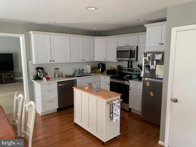 a kitchen with stainless steel appliances white cabinets and wooden floor
