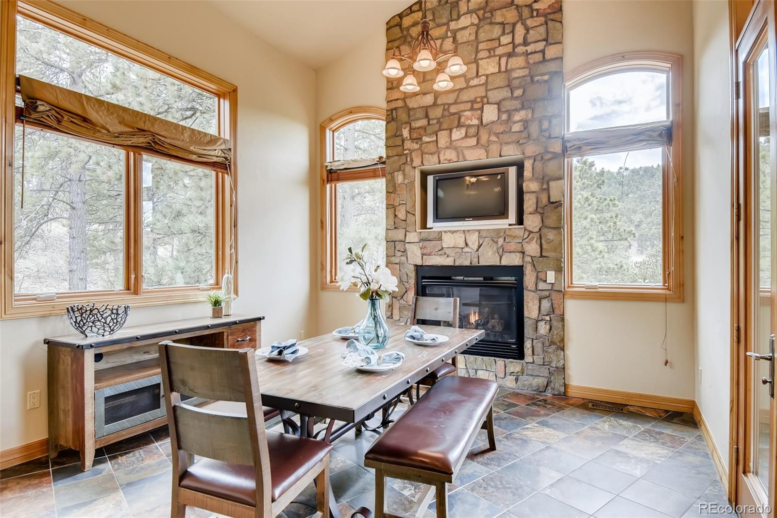 1265 Silver Rock Lane Evergreen, CO 80439 - Photo 13 of 35 a dining room with furniture a fireplace and large windows