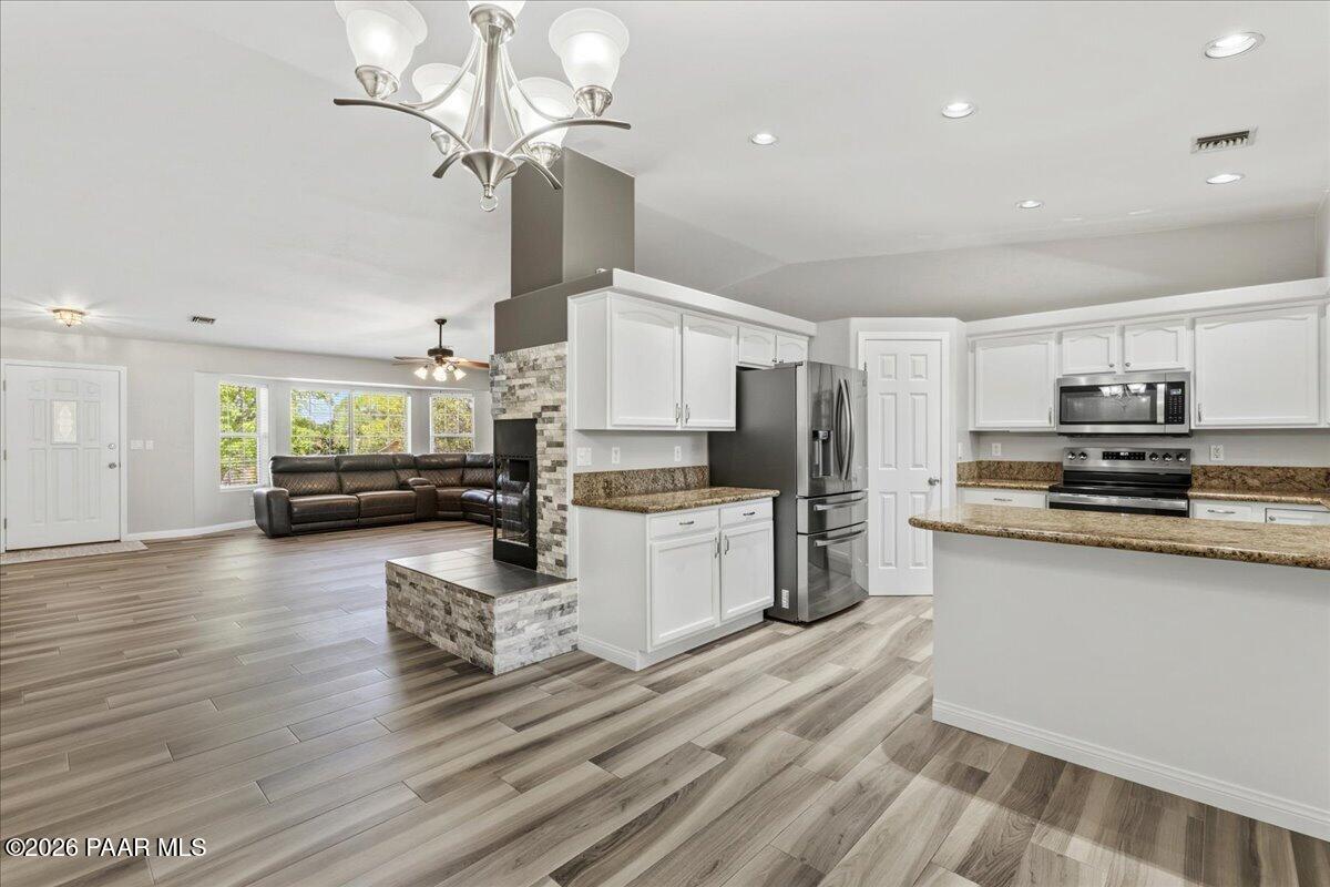 4701 North Spring Drive Prescott Valley, AZ 86314 - Photo 9 of 31 a kitchen with stainless steel appliances kitchen island granite countertop a refrigerator a stove top oven a sink dishwasher and white cabinets with wooden floor