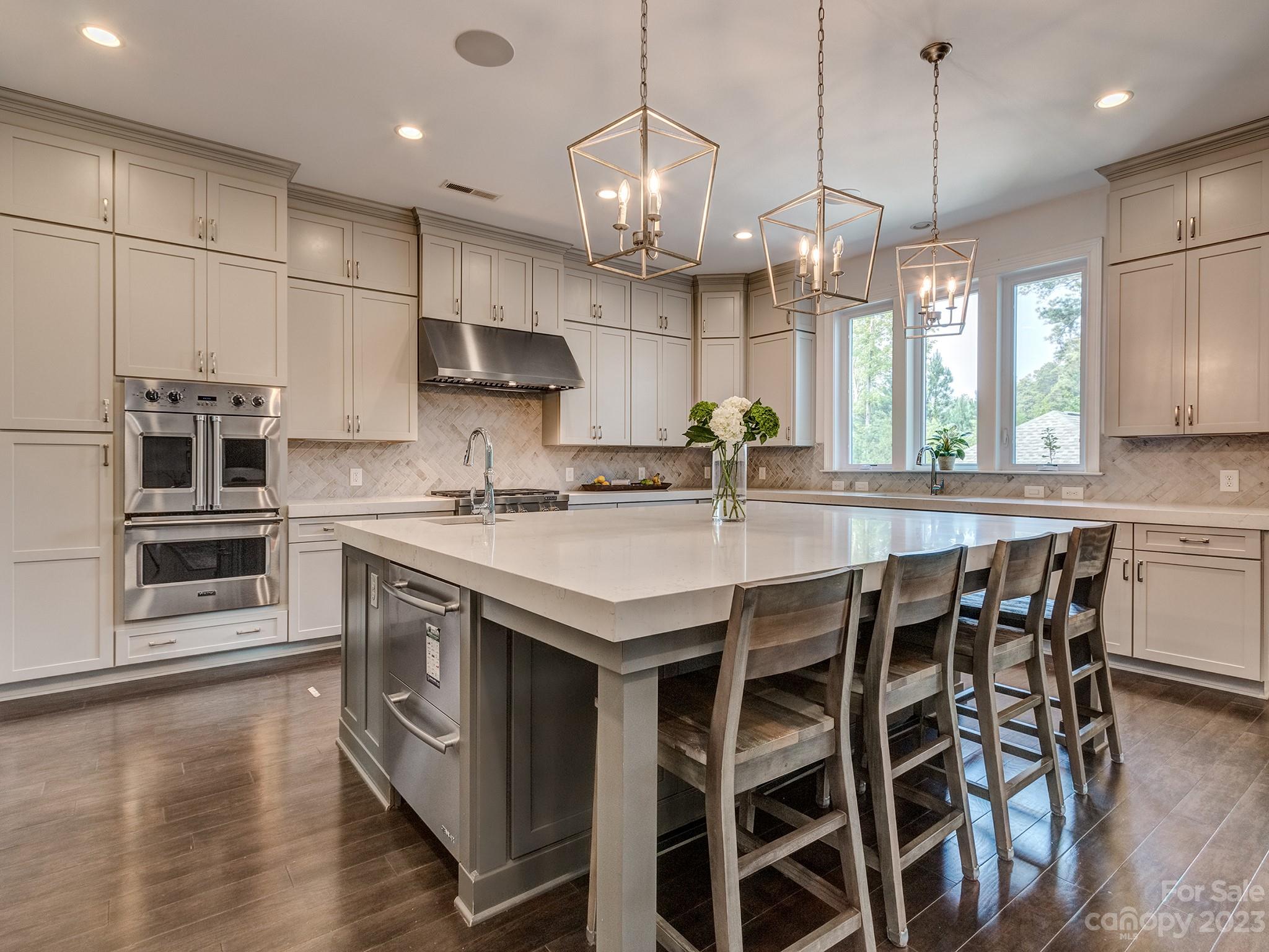 411 Turtleback Ridge Weddington, NC 28104 - Photo 7 of 48 a kitchen with stainless steel appliances granite countertop a sink a stove a microwave a island with wooden floor and cabinets